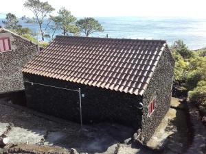 un edificio con techo de baldosa con el océano en el fondo en Adega Ramalho, en Canto da Areia