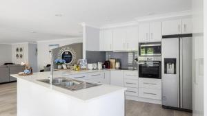 a kitchen with white cabinets and a stainless steel refrigerator at Serenity in Corlette