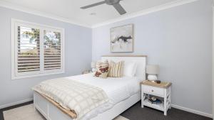 a white bedroom with a bed and a window at Serenity in Corlette