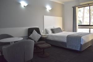 a bedroom with a bed and a chair and a table at Riviana Motel in Deniliquin +16 photos