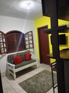 a living room with a couch with two red pillows at Hospedaria D' Gabi in São Pedro da Aldeia
