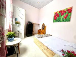 a small room with a bed and a table and a refrigerator at La Mera Homestay in Ben Tre