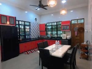 a kitchen with a table and chairs and red cabinets at Sweethome MAMA in Kuala Terengganu