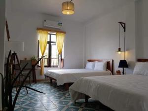 a hotel room with two beds and a window at La Mera Homestay in Ben Tre