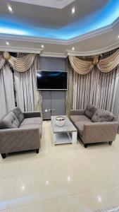 a living room with two couches and a flat screen tv at Suite Room with big balcony in Al Rahba +23 photos