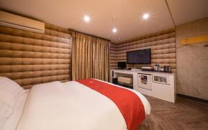 a bedroom with a bed and a desk with a television at R Hotel in Bucheon