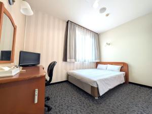 a bedroom with a bed and a desk with a television at Suizenji Comfort Hotel in Kumamoto
