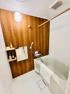 a bathroom with a tub and a wooden wall at Private Room near Iriya in Tokyo +40 photos