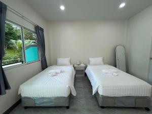 two twin beds in a room with a window at Karon Little House in Karon Beach