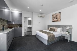 a white bedroom with a bed and a kitchen at North Adelaide Boutique Stays Accommodation in Adelaide
