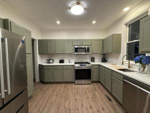 a kitchen with green cabinets and a stainless steel refrigerator at Spacious 4BR Home Pool and Comfort in Columbus