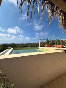 ein Swimmingpool mit Stühlen an der Seite eines Hauses in der Unterkunft Cabañas Mizontle in Mazunte