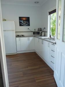 a kitchen with white cabinets and a sink and a window at Bushland Breeze - Self Contained Unit in Gladstone
