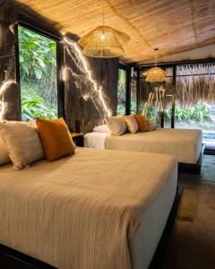 two beds in a room with large windows at Jungla EcoLuxury Resort in Villeta