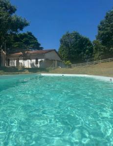 a pool of blue water in front of a house at Pousada Villa Felicidade in Guarapari