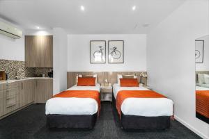 a room with three beds with orange and white sheets at North Adelaide Boutique Stays Accommodation in Adelaide