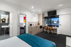 a bedroom with a bed and a desk and a kitchen at North Adelaide Boutique Stays Accommodation in Adelaide