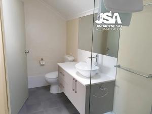 a white bathroom with a sink and a toilet at Parkwood 7 in Jindabyne +5 photos