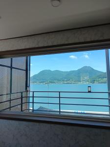 a window with a view of the water and mountains at Namhae Soljeong Pension in Namhae