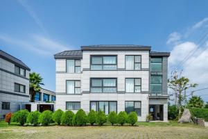 an apartment building with bushes in front of it at Jeju Aromtarom House in Jeju