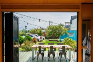 a table and chairs on a deck with a view of a yard at Jeju Aromtarom House in Jeju