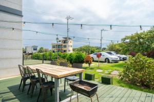 a wooden table and chairs on a patio at Jeju Aromtarom House in Jeju