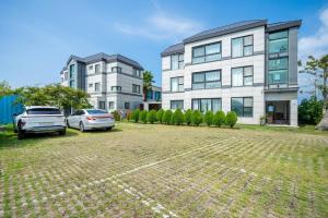 a building with two cars parked in a parking lot at Jeju Aromtarom House in Jeju +12 photos