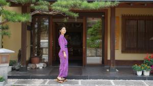 a woman is standing in front of a building at Bouzantei Kotobuki in Ueda
