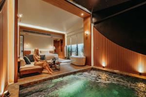 a woman sitting in a room with a swimming pool at K2Green Hotel in Kanchanaburi City