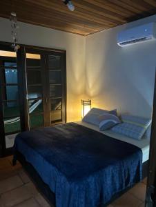 a bedroom with a bed with blue sheets and a window at Lar Zen in Garopaba