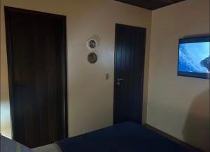 a bedroom with a door and a tv on the wall at Lar Zen in Garopaba