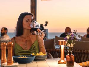 a woman drinking a glass of wine at a table at Secana Beachtown Resort & Villas in Canggu