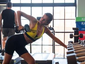 a woman lifting a dumbbell in a gym at Secana Beachtown Resort & Villas in Canggu