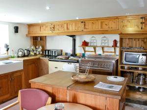 a kitchen with wooden cabinets and an island with a table at The Barn in Waberthwaite