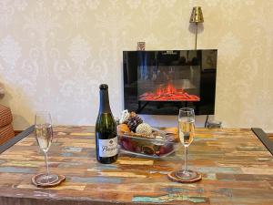 a bottle of wine and two glasses on a table with a fireplace at Mystified Bungalow in West Burton