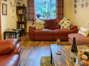 a living room with brown leather couches and a table at Mystified Bungalow in West Burton