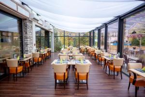a restaurant with tables and chairs and windows at Hotel Victoriya in Kaprun