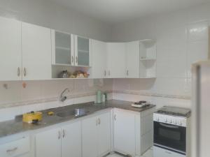 a kitchen with white cabinets and a sink at Melos hospedagem jp in João Pessoa