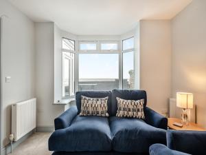 a blue couch in a living room with a window at Stones Throw Cottage in Sheringham
