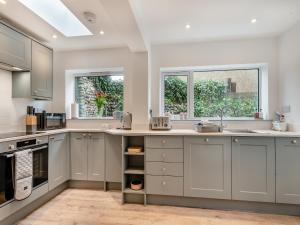a kitchen with gray cabinets and a sink at Stones Throw Cottage in Sheringham