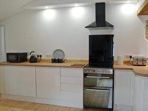 a kitchen with white cabinets and a stove top oven at No2 The Neuk in Belford
