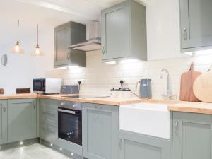 a kitchen with gray cabinets and white appliances at Middle Hanter - Uk37355 in Old Radnor