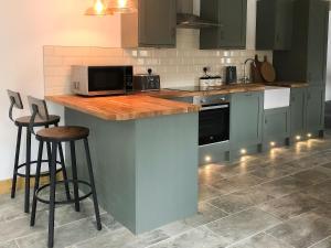 a kitchen with green cabinets and a counter with stools at Middle Hanter - Uk37355 in Old Radnor +24 photos
