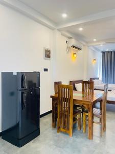 a kitchen and dining room with a table and a refrigerator at Yehara Apartments in Weligama