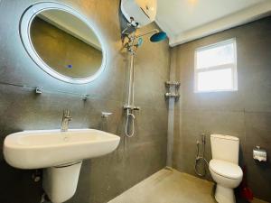 a bathroom with a sink and a toilet and a mirror at Yehara Apartments in Weligama