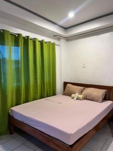 a bed in a room with green curtains at Ace Travellers Inn- Palawan in Puerto Princesa City