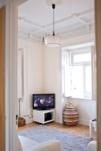 a white living room with a television and a window at Villa Charme in Estoril