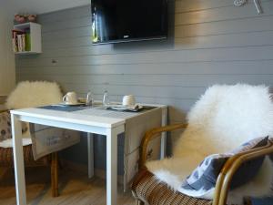 einen weißen Tisch mit 2 Stühlen und einen TV an der Wand in der Unterkunft Entre monts et collines B&B et espace détente in Mont-de-l'Enclus