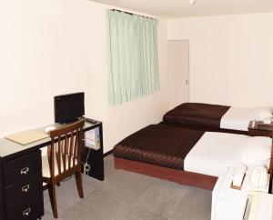 Sakura Hotel Oami في Ōami: غرفة في الفندق بها سرير ومكتب وبه جهاز كمبيوتر