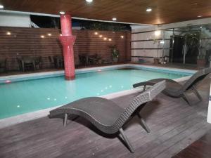a swimming pool with two chairs and a red column at Townhouse Oak Vera Hotel Near Clark International Airport in Angeles